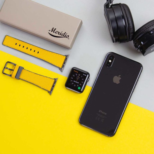 Submarine-Apple-watch-yellow-rubber-band-on-top-of-yellow-surface-with-balck-earphone-bs