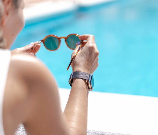 Apple-watch-black-tide-band-recycled-ocean-plastic-woman-handles-own-eyewear-close-to-a-swimming-pool